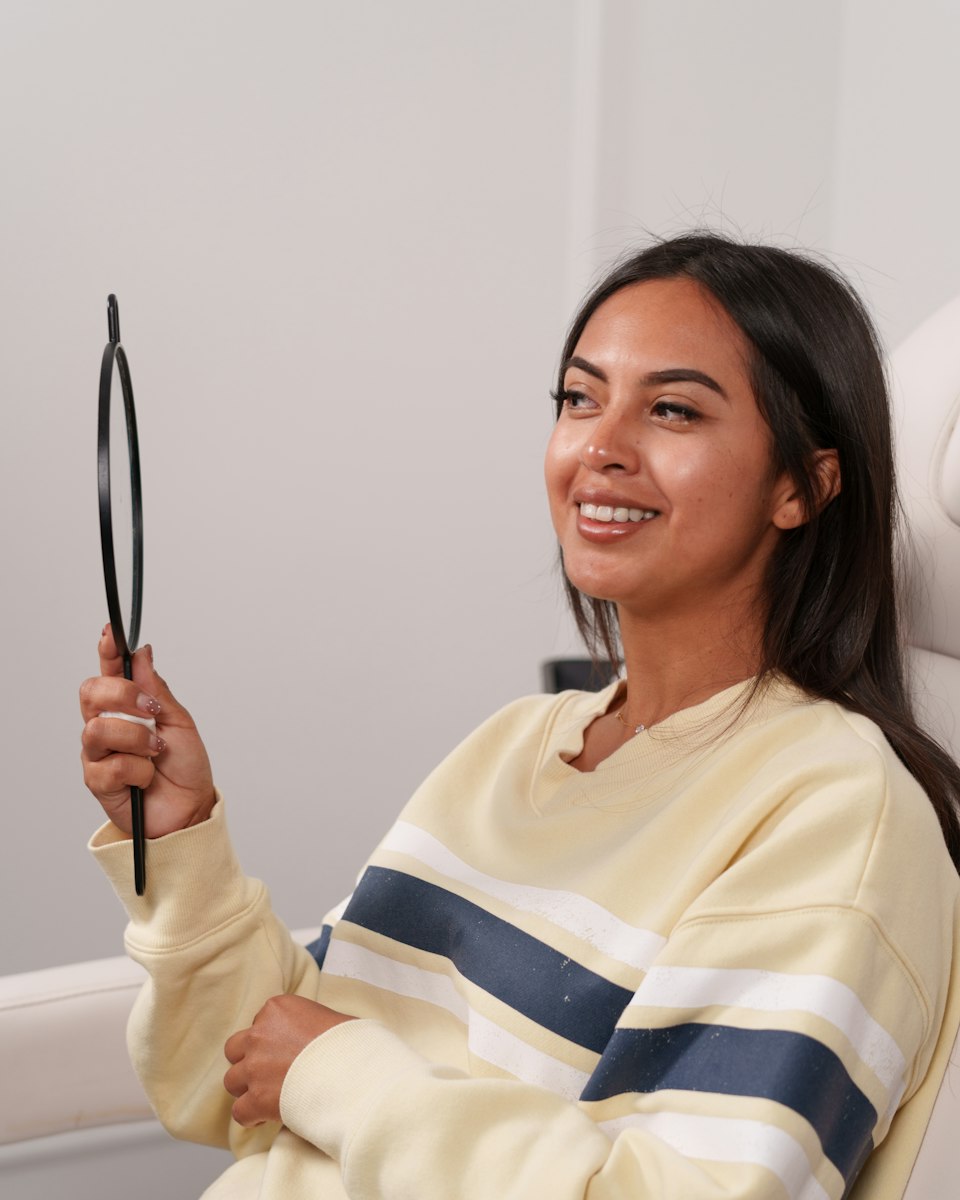 Paciente mirándose la sonrisa en un espejo en el sillón dental